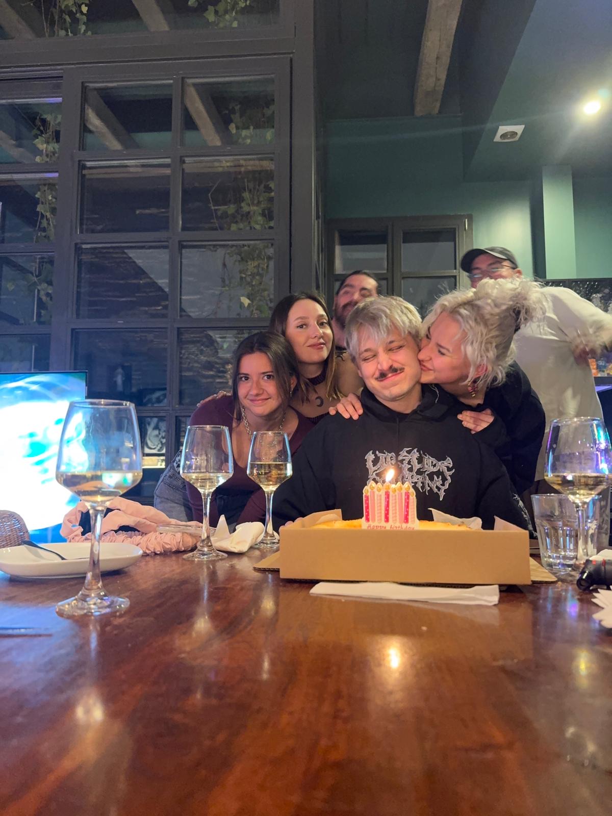 Jean surrounded by close friends at a birthday dinner, a candlelit cake on the table